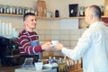 Barista serving cup of coffee to customer at counter in small coffee shop Royalty Free Stock Photo